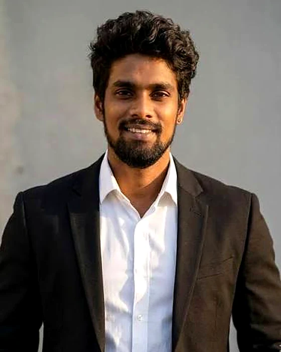 Ankith Reddy, in a dark blazer and open white shirt, against a plain wall.